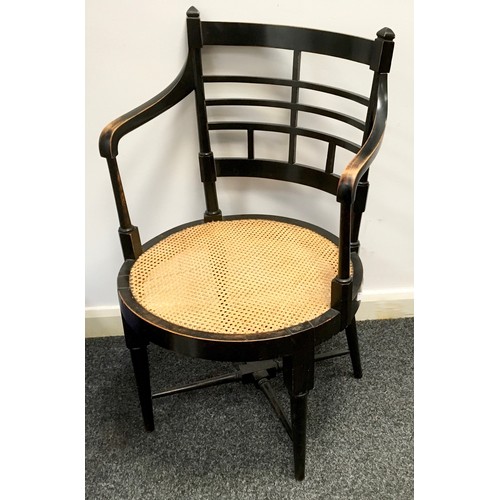 193 - An E W Godwin Aesthetic movement ebonised open arm chair, stepped Geometric back, caned seat, taperi... 