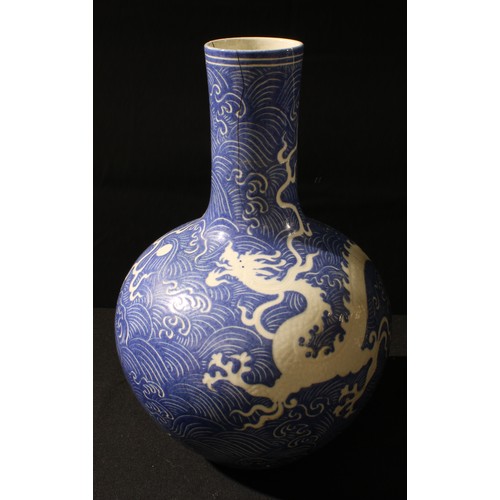 3228 - A large Chinese porcelain bottle vase, incised with a ferocious dragon pursuing a pearl on a ground ... 