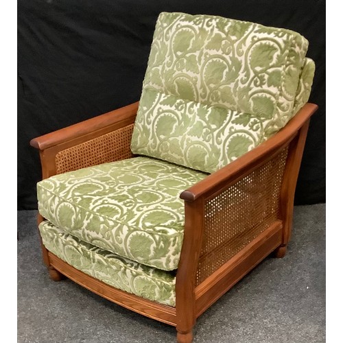 87 - An Ercol golden oak bergere armchair, green and cream cushioned back and seat