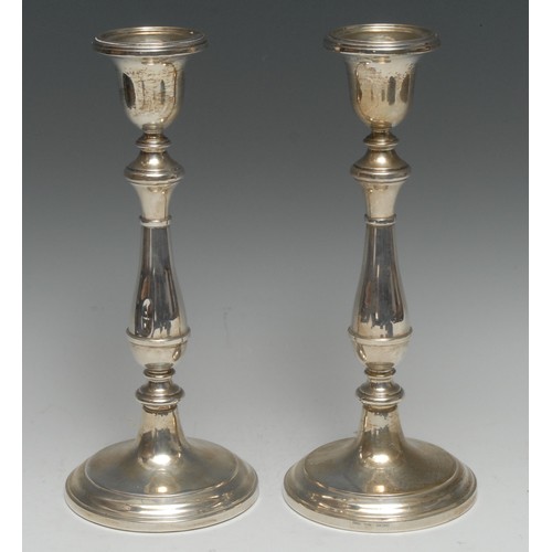 139 - A pair of Elizabeth II silver table candlesticks, bell shaped sconces, knopped stems, domed circular... 