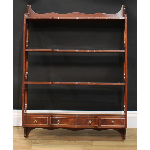 117 - A near pair of mahogany wall shelves, each with three shaped serpentine front shelves above three dr... 