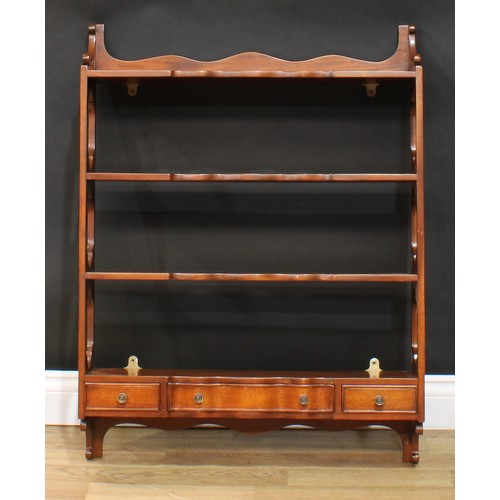 117 - A near pair of mahogany wall shelves, each with three shaped serpentine front shelves above three dr... 