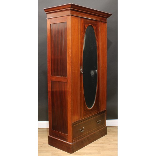 120 - An Edwardian mahogany wardrobe, outswept cornice with faux-dentil parquetry apron above an oval beve... 