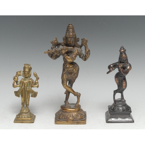 3352 - An Indian bronze murti, Krishna, playing a bansuri, 20.5cm high, 19th/early 20th century; others (3)