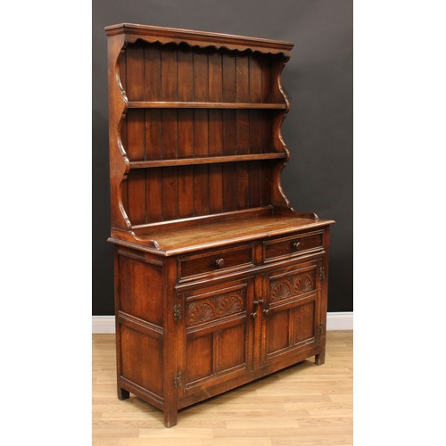 214 - An 18th century style oak dresser, moulded cornice above a shaped apron and two plate racks, the bas... 