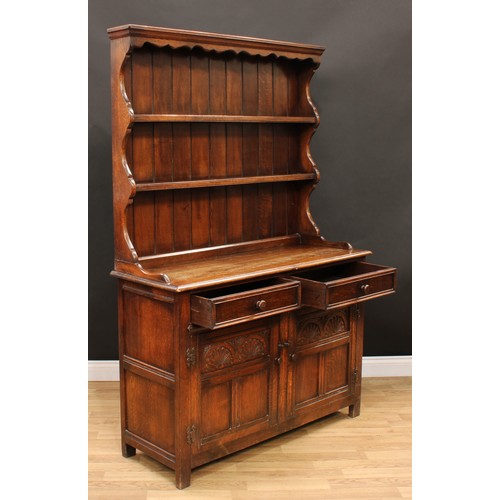 214 - An 18th century style oak dresser, moulded cornice above a shaped apron and two plate racks, the bas... 