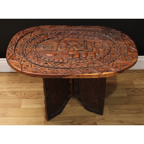 217 - A softwood low table, carved in the African tribal art taste with figures and huts, 48cm high, 75cm ... 