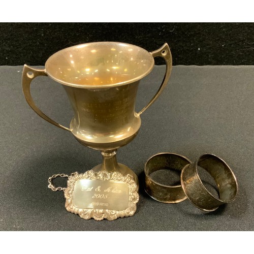 394 - A George V silver twin handled trophy cup, Sheffield 1931;  a pair of silver napkin rings;  a decant... 