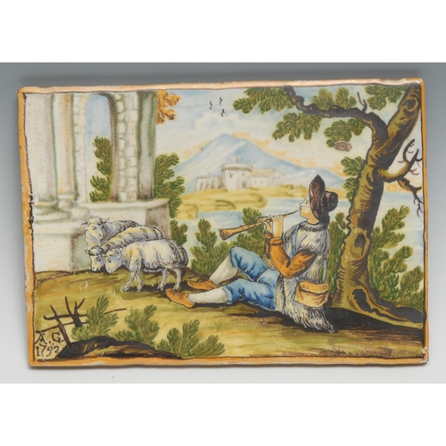 447 - An Italian maiolica rectangular panel, possibly Castelli, painted in polychrome with a shepherd besi... 