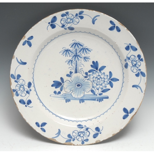 444 - An English 18th century Delft charger, decorated in underlaze blue with stylised flowers and bamboo,... 