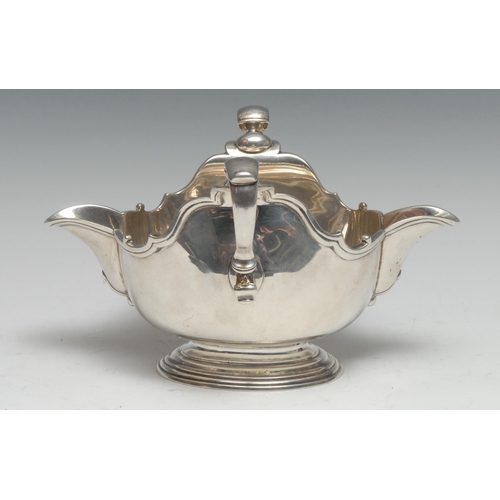 260 - An 18th century silver double-lipped sauceboat, capped-double scroll handles, piecrust borders, step... 