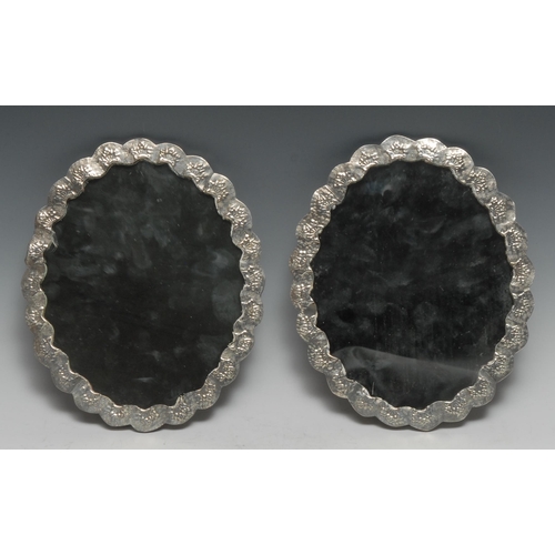 194 - A pair of Turkish silver shaped oval mirrors, chased with flowers and applied with peacocks, 22cm wi... 