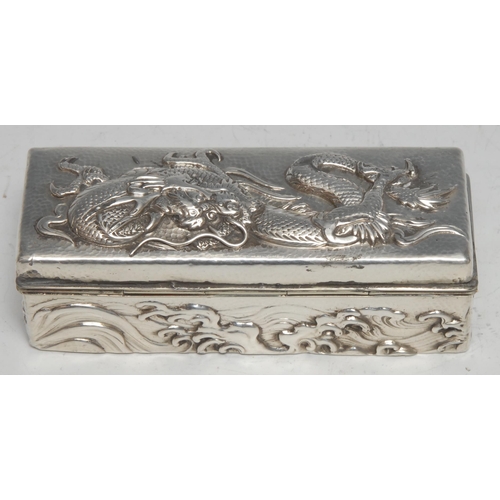 84 - A Chinese silver rectangular box, in relief with a ferocious dragon amongst scrolling clouds, on a p... 