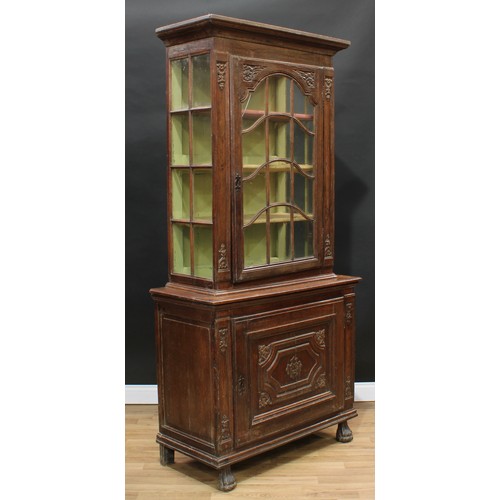 1976 - An 18th century Continental oak display cabinet, outswept cornice above an astragal glazed door encl... 