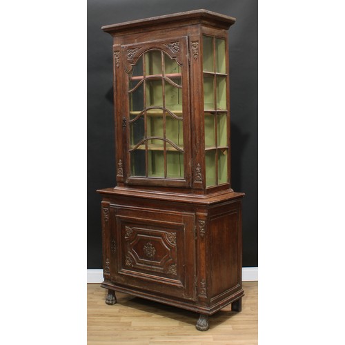 1976 - An 18th century Continental oak display cabinet, outswept cornice above an astragal glazed door encl... 