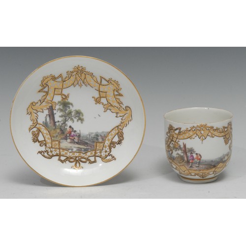 757A - A Meissen bell-shaped coffee cup and saucer, well-painted with a pair of rustics travelling through ... 