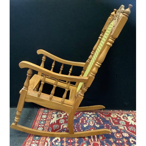 95 - A 20th century pine rocking chair, carved cresting, cane back, turned supports, 110cm high.