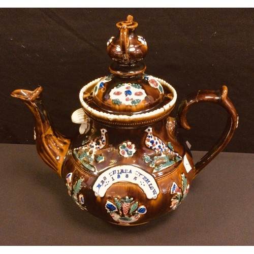 209 - A Victorian barge ware treacle glazed teapot and cover, late 19th century, moulded with pheasant wit... 