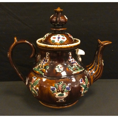 209 - A Victorian barge ware treacle glazed teapot and cover, late 19th century, moulded with pheasant wit... 