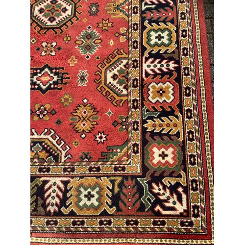 249 - A large Turkish Amara woollen carpet, all over decorated with geometric medallions, red ground, six ... 