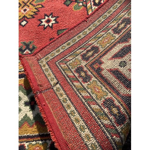 249 - A large Turkish Amara woollen carpet, all over decorated with geometric medallions, red ground, six ... 