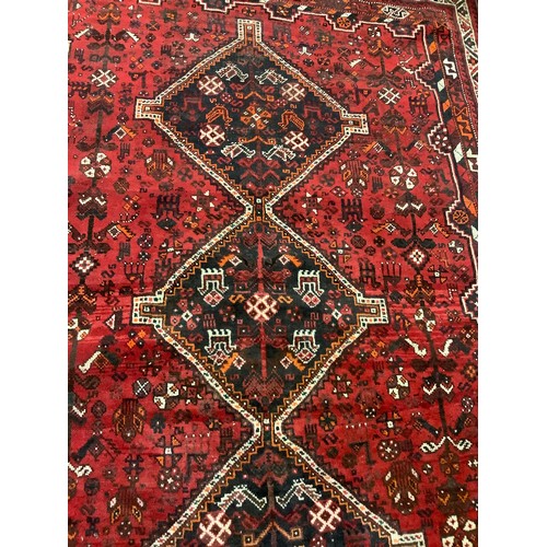 252 - An early to mid 20th century Persian Shiraz wool rug, hand-knotted in deep red, the central field wi... 