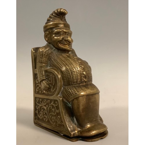 431 - A novelty brass vesta case, as Mr Punch, seated in a chair, hinged striker base, 6cm high, c.1900.