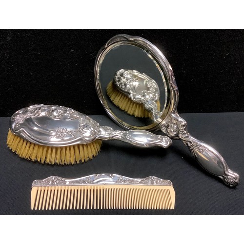 95 - An associated George V silver three piece hand mirror and hair brush set, embossed with scrolling fl... 