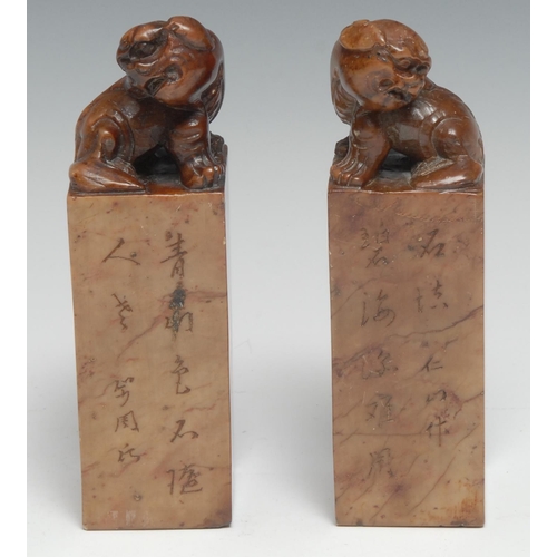 223 - A pair of Chinese soapstone seals, each crested by a temple lion and carved with verse, 13.5cm high;... 