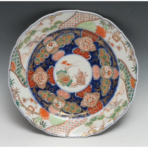 260 - A Japanese shaped circular charger, the centre painted in the Imari palette with precious objects an... 