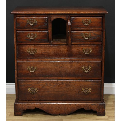 215 - An oak chest, rectangular top, four short drawers centred by an arched cupboard door above three lon... 