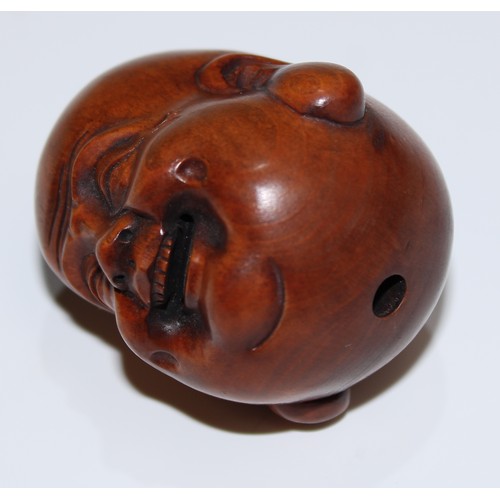 5168 - A Japanese boxwood netsuke, carved as the head of Buddha, smiling, 4cm long, signed