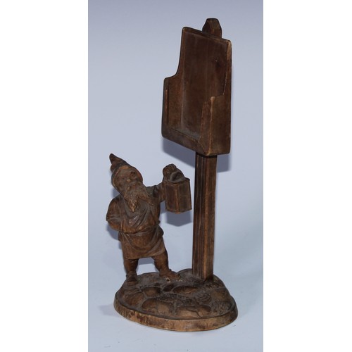 5077 - A Black Forest novelty country house menu stand, carved as a gnome holding a lantern beneath a sign ... 