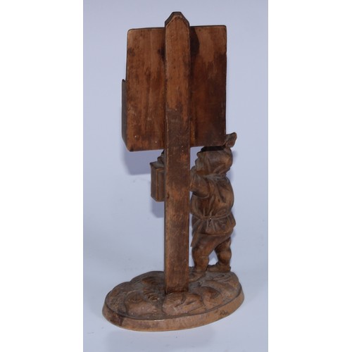 5077 - A Black Forest novelty country house menu stand, carved as a gnome holding a lantern beneath a sign ... 