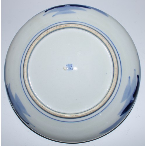 5172 - A Japanese porcelain circular dish, painted in underglaze blue with a figure atop a rock in a monume... 