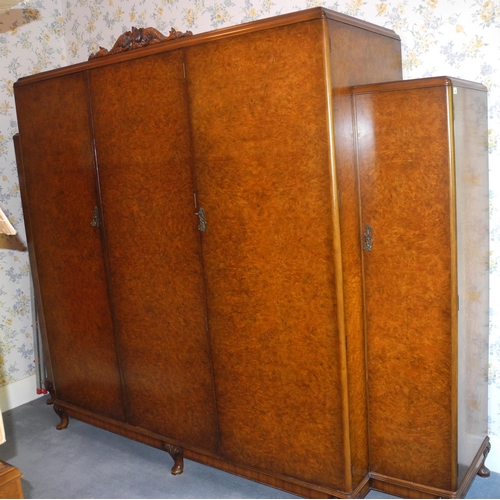 143 - A large burr walnut break centre wardrobe, dolphin carved cresting;  a conforming chest of four long... 