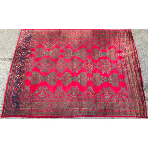 651 - A Persian style carpet, geometric green and blue design on red ground, 430cm long x 340cm wide