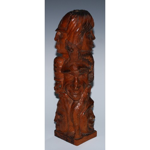 27 - An adzed oak library desk sculpture, as a multi-bust totem pole, carved with heads from varying trad... 