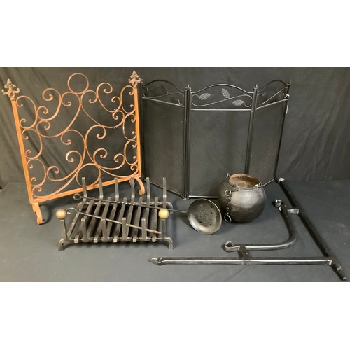 721 - A cast metal fire grate; a wrought iron fire screen; a folding fire screen; a cast iron cook pot wit... 