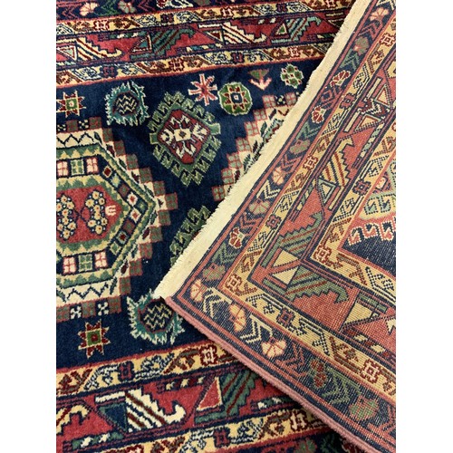 136 - A hand-made Heriz runner carpet, woven with stylised geometric motifs in shades of red, pale green, ... 