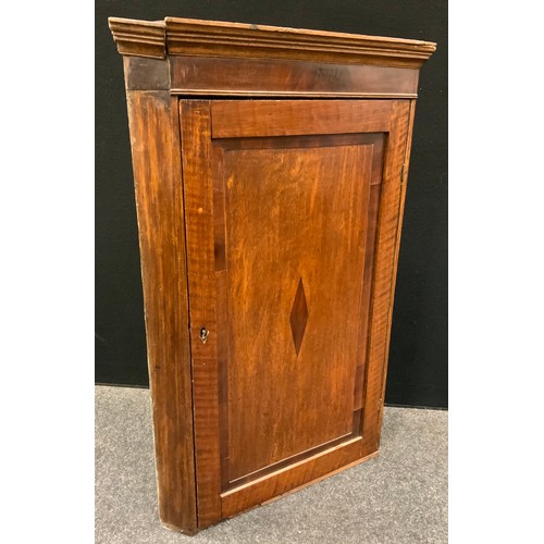 141 - A George III oak corner cupboard, moulded cornice, the field panelled door inlaid with mahogany loze... 