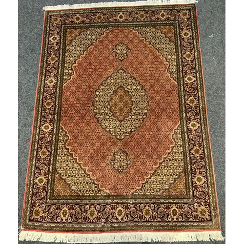 146 - A fine Persian, hand-made, Tabriz rug / carpet, woven with stylised floral motifs in shades of burgu... 