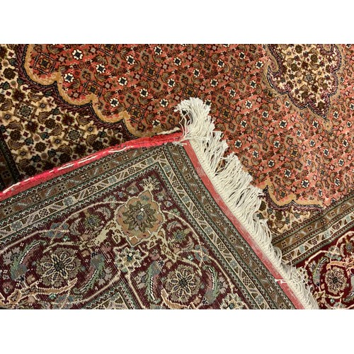 146 - A fine Persian, hand-made, Tabriz rug / carpet, woven with stylised floral motifs in shades of burgu... 