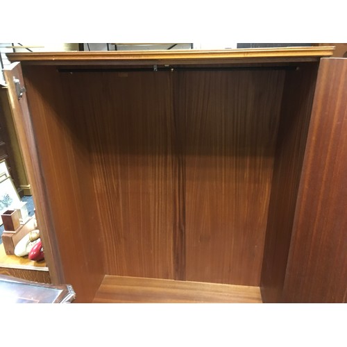 147 - A mid 20th century oak veneered bedroom suite by Austinsuite, comprising two double wardrobes and a ... 