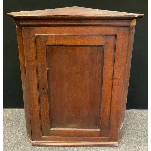 149 - A George III oak splay front wall hanging corner cupboard, rectangular panel door enclosing two shap... 