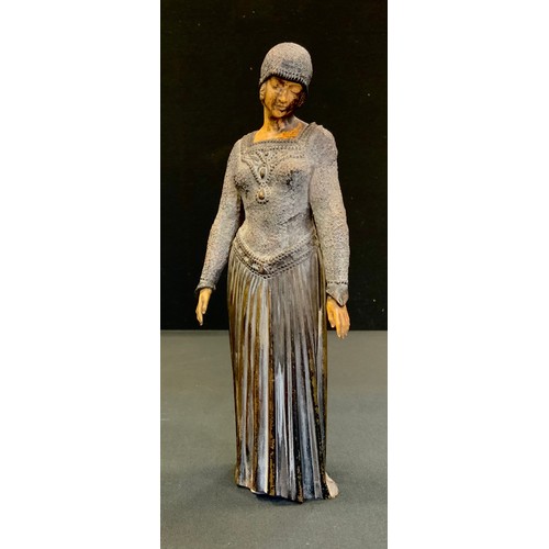 90 - An Art Deco style elephantine type figure, of a lady wearing a beaded cap and long dress, 23cm high