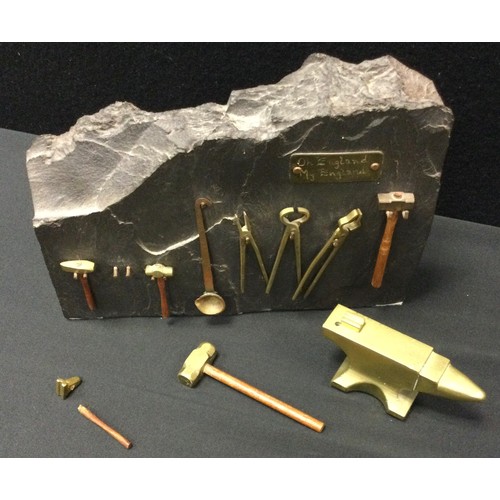 112 - A miniature brass anvil and tool set, This England, My England inc sledgehammer, tongs. smelting bow... 