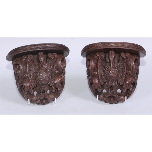 5163 - A pair of 19th century Anglo-Indian hardwood wall brackets, each carved with a pelican in her piety,... 