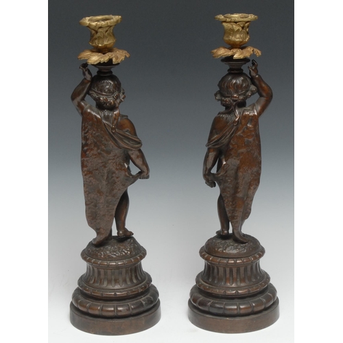 5187 - A pair of sculptural 19th century French bronzed and parcel-gilt figural candlesticks, each cast as ... 