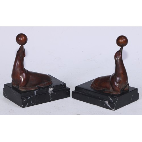 5171 - A pair of Art Deco design brown patinated bronze bookends, each cast with a seal balancing a ball, s... 